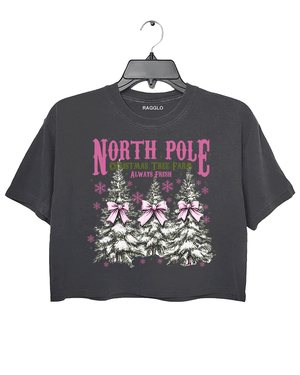 Ragglo dark gray crop top featuring three Christmas trees with pink bows and snowflakes, with 'NORTH POLE CHRISTMAS TREE FARM ALWAYS FRESH' text, perfect for festive holiday streetwear.

