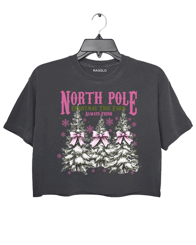 Ragglo dark gray crop top featuring three Christmas trees with pink bows and snowflakes, with 'NORTH POLE CHRISTMAS TREE FARM ALWAYS FRESH' text, perfect for festive holiday streetwear.

