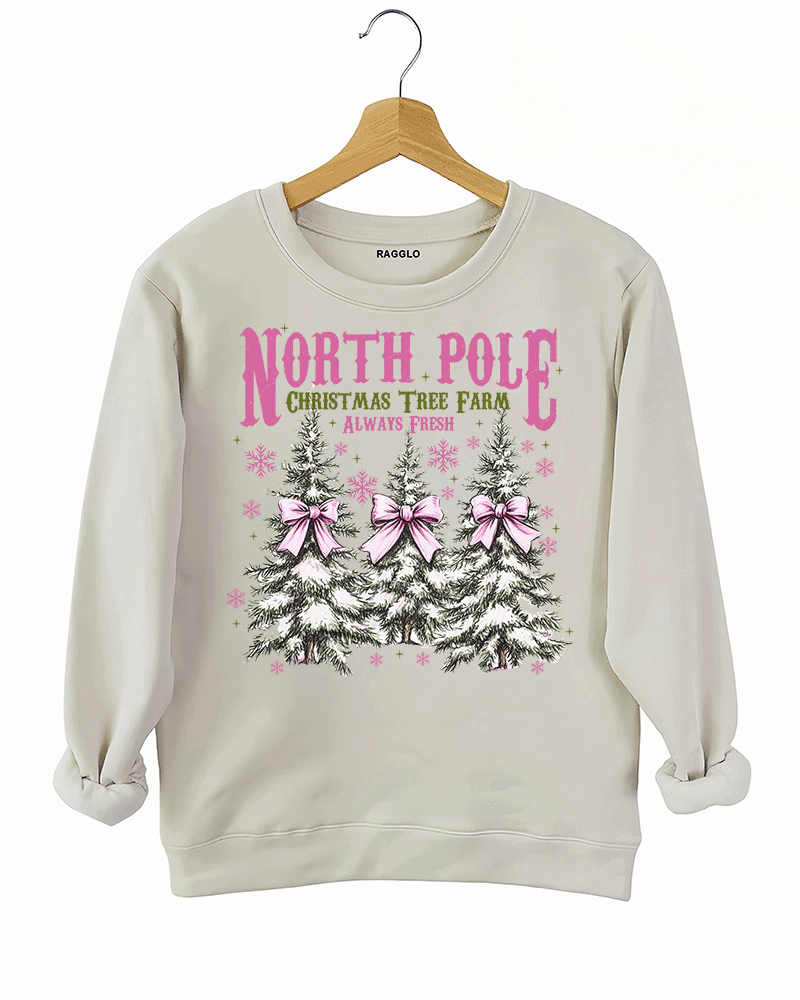 Ragglo beige sweatshirt featuring three Christmas trees with pink bows and snowflakes, with 'NORTH POLE CHRISTMAS TREE FARM ALWAYS FRESH' text, perfect for festive holiday streetwear.

