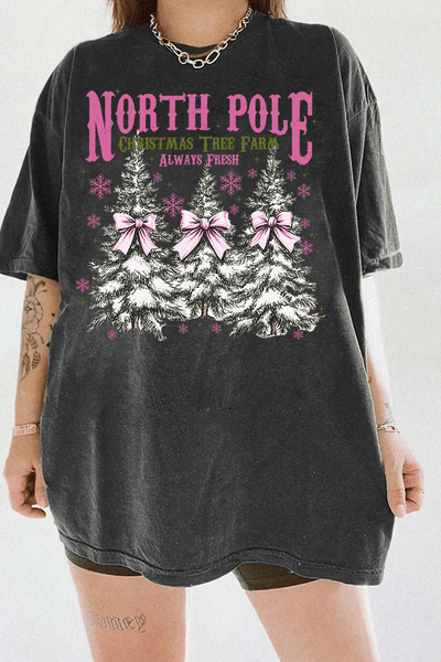 Ragglo dark gray tee featuring three Christmas trees with pink bows and snowflakes, with 'NORTH POLE CHRISTMAS TREE FARM ALWAYS FRESH' text, perfect for festive holiday streetwear.

