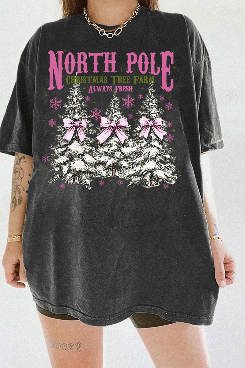 Ragglo dark gray tee featuring three Christmas trees with pink bows and snowflakes, with 'NORTH POLE CHRISTMAS TREE FARM ALWAYS FRESH' text, perfect for festive holiday streetwear.

