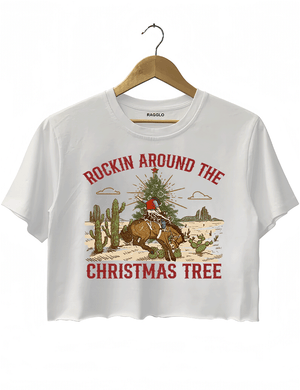 Ragglo white crop top featuring a cowboy riding a horse with a Christmas tree in a desert scene with cacti, with 'ROCKIN AROUND THE CHRISTMAS TREE' text, perfect for festive western-style streetwear.

