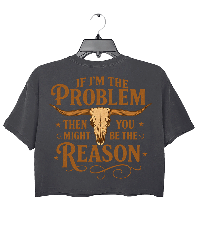 Dark gray crop top with the text 'IF I'M THE PROBLEM THEN YOU MIGHT BE THE REASON' in bold orange font across the back, accompanied by a bull skull illustration.