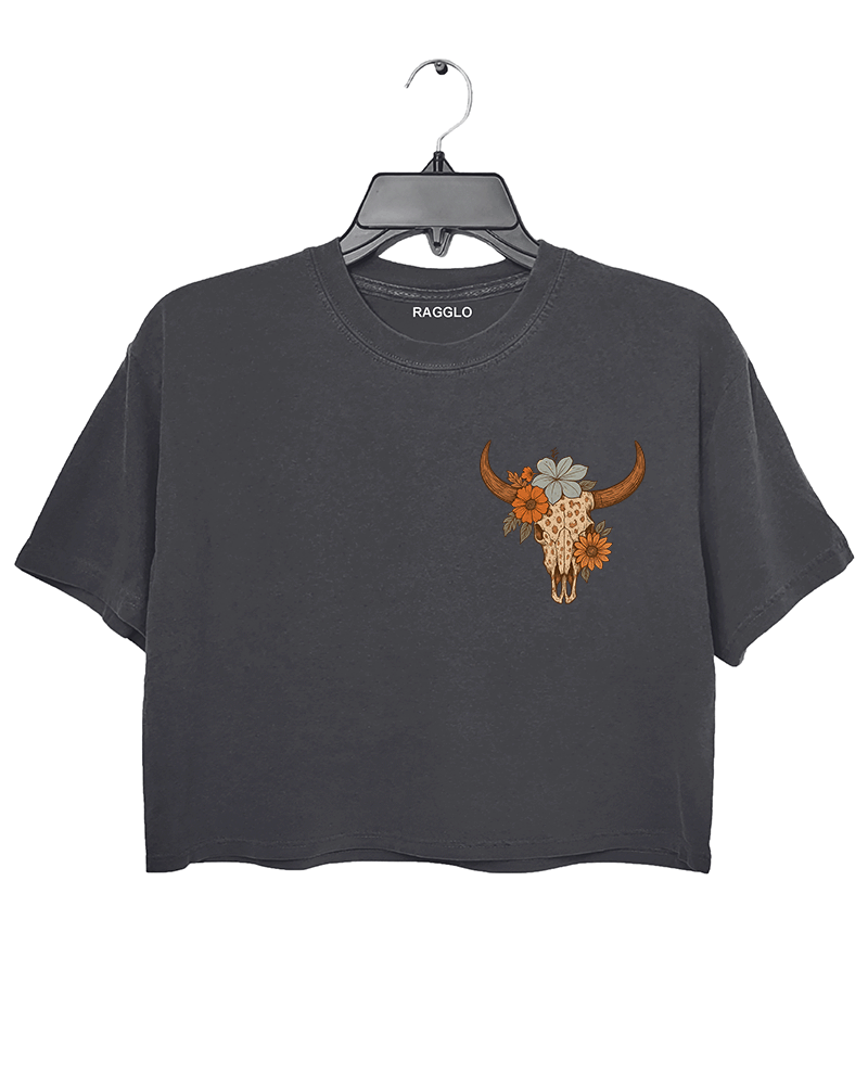 Dark gray crop top featuring a bull skull design adorned with floral elements on the front. The graphic has a warm orange tone and is positioned centrally.