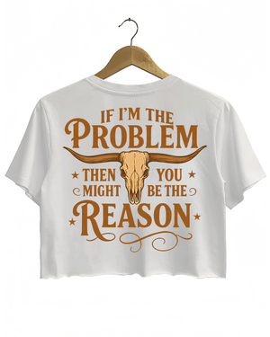 White crop top with the phrase 'IF I'M THE PROBLEM THEN YOU MIGHT BE THE REASON' written in bold orange font on the back, along with a bull skull illustration.