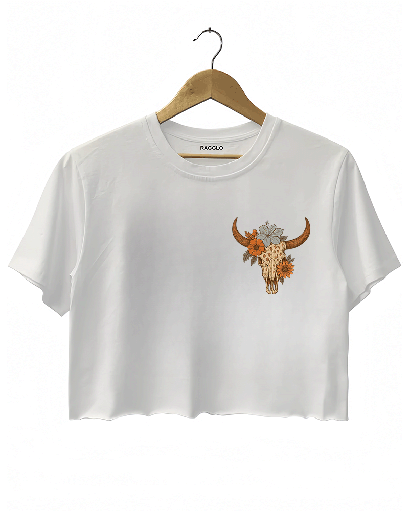 White crop top featuring a bull skull design with floral details on the front. The graphic is in a contrasting warm orange tone, giving it a bold look.