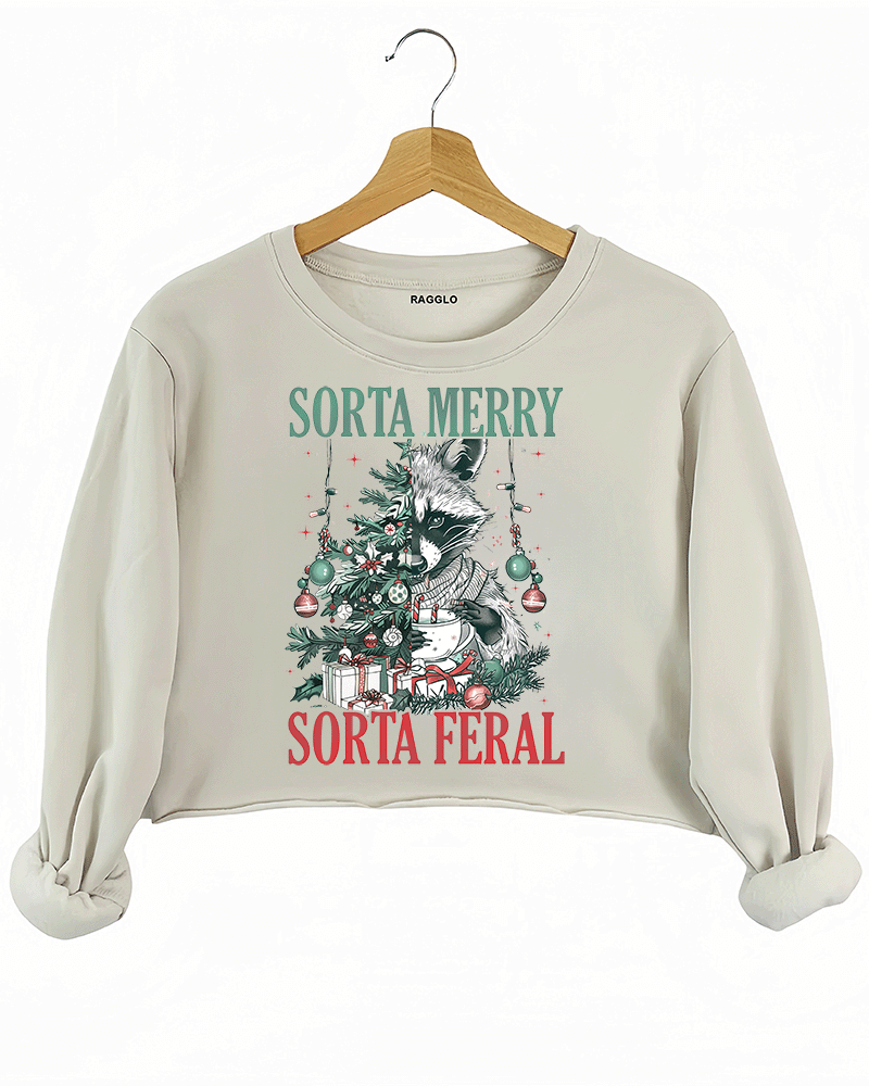 Ragglo beige crop sweatshirt featuring a raccoon with a decorated Christmas tree, gifts, and 'SORTA MERRY SORTA FERAL' text, perfect for funny Christmas streetwear.

