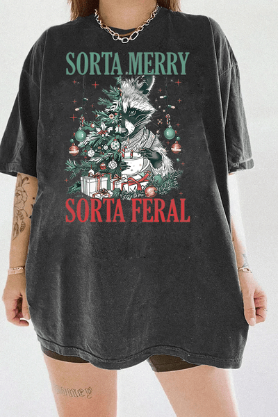Ragglo dark gray tee featuring a raccoon with a decorated Christmas tree, gifts, and 'SORTA MERRY SORTA FERAL' text, perfect for funny Christmas streetwear.

