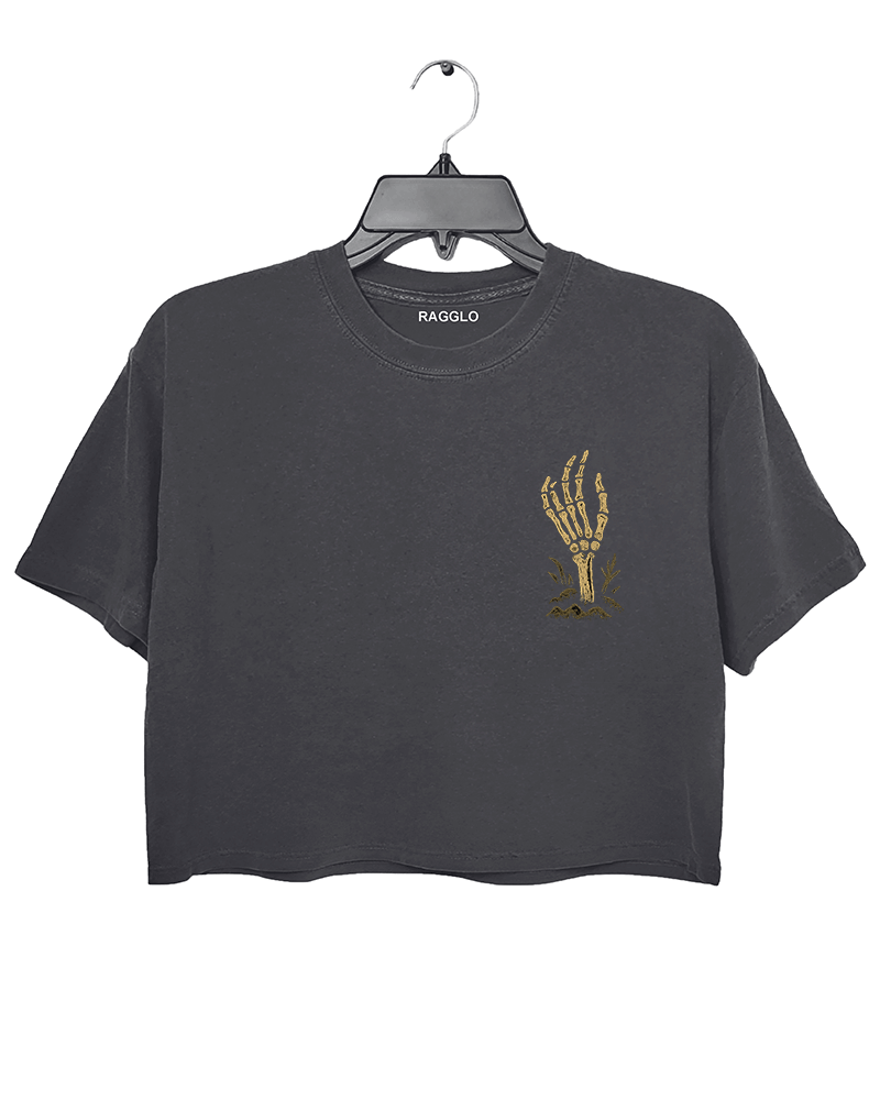Front view of a dark gray cropped Halloween T-shirt by RAGGLO, featuring a minimalist gold skeleton hand graphic holding a flame on the left chest. Subtle yet spooky, ideal for a low-key Halloween vibe.
