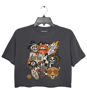 Dark gray crop top featuring a bold graphic design with various motifs, including a flaming skull, a dice with number 8, a red lip with teeth, a leopard's face, and the word 'darlin' in cursive. The design also includes the phrase 'FUCK WHAT THEY THINK' and a few additional skulls and vintage-style elements, combining punk and retro aesthetics.