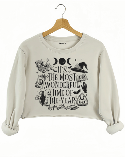 Ragglo beige crop sweatshirt featuring witchy elements like moons, bats, a witch hat, spellbook, and potion bottle, with 'IT’S THE MOST WONDERFUL TIME OF THE YEAR' text, perfect for magical Halloween streetwear.

