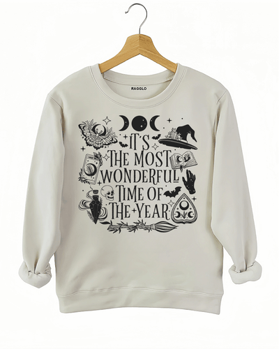 Ragglo beige sweatshirt featuring witchy elements like moons, bats, a witch hat, spellbook, and potion bottle, with 'IT’S THE MOST WONDERFUL TIME OF THE YEAR' text, perfect for magical Halloween streetwear.

