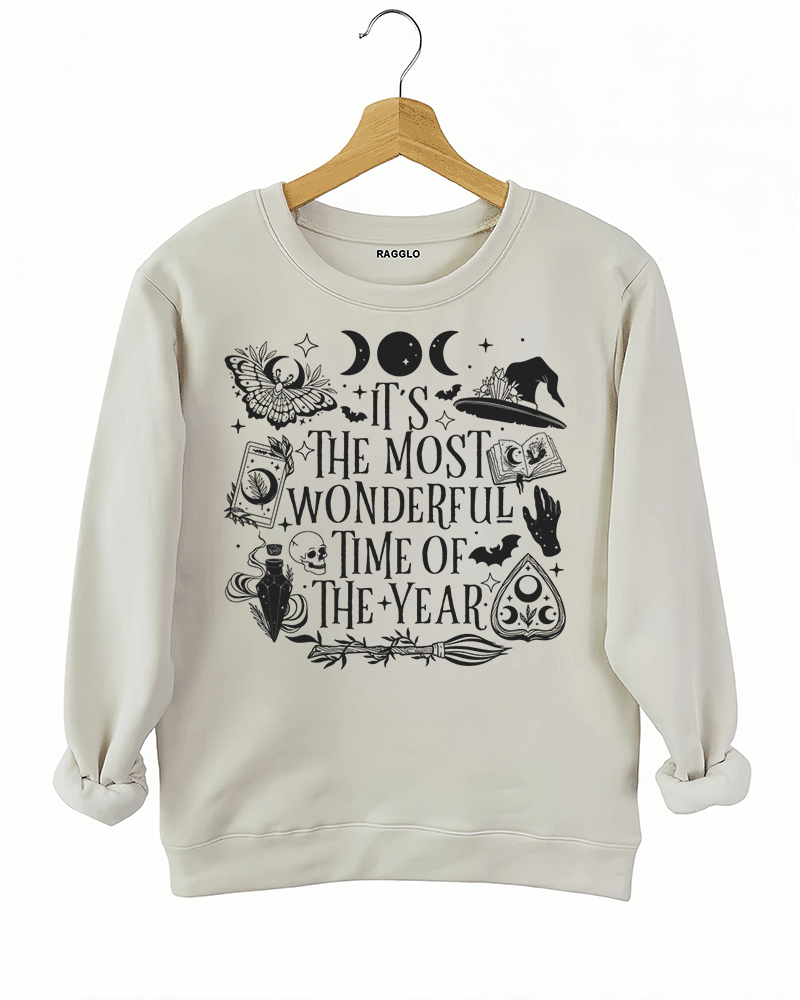 Ragglo beige sweatshirt featuring witchy elements like moons, bats, a witch hat, spellbook, and potion bottle, with 'IT’S THE MOST WONDERFUL TIME OF THE YEAR' text, perfect for magical Halloween streetwear.

