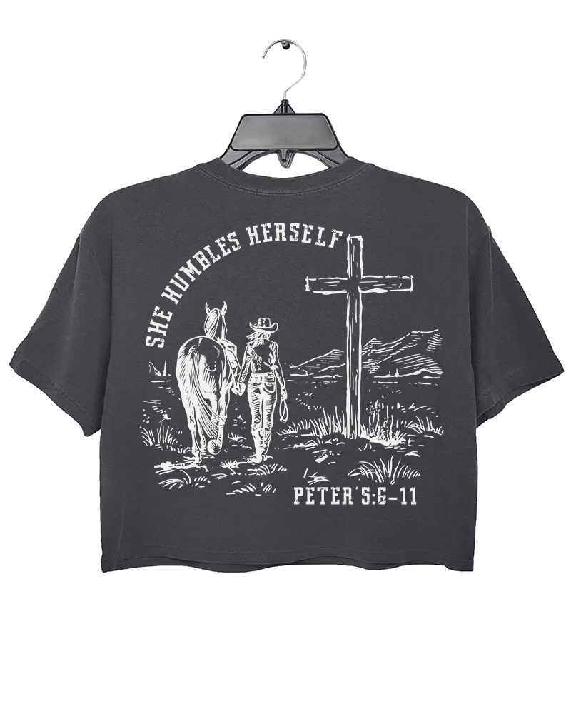 Dark Gray Ragglo women's crop t-shirt with 'She Humbles Herself' text, a cowgirl walking with a horse, a cross, and Peter 5:6-11 scripture, perfect for Christian and western-style apparel

