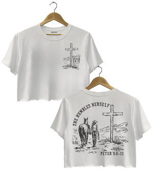 White Ragglo women's crop t-shirt featuring front and back designs with 'She Humbles Herself' text, a cowgirl with a horse, a cross, and Peter 5:6-11 scripture, perfect for Christian faith and western-inspired fashion.

