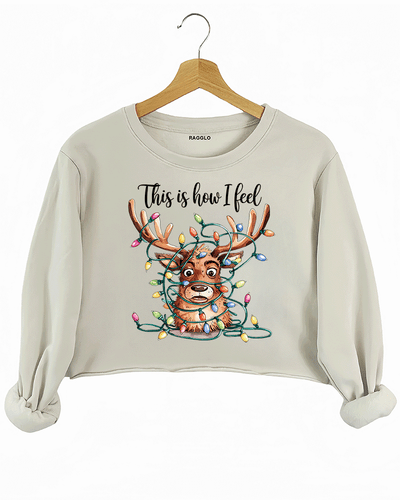 Beige crop sweatshirt featuring a reindeer caught in colorful Christmas lights, with the playful text 'This is how I feel,' available on Ragglo.
