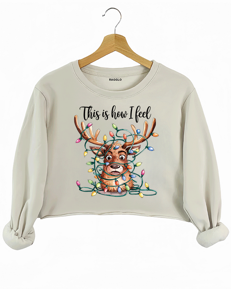 Beige crop sweatshirt featuring a reindeer caught in colorful Christmas lights, with the playful text 'This is how I feel,' available on Ragglo.