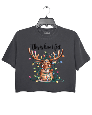 Dark gray crop top featuring a cartoon reindeer tangled in colorful Christmas lights with a humorous expression, accompanied by the text 'This is how I feel,' available on Ragglo.