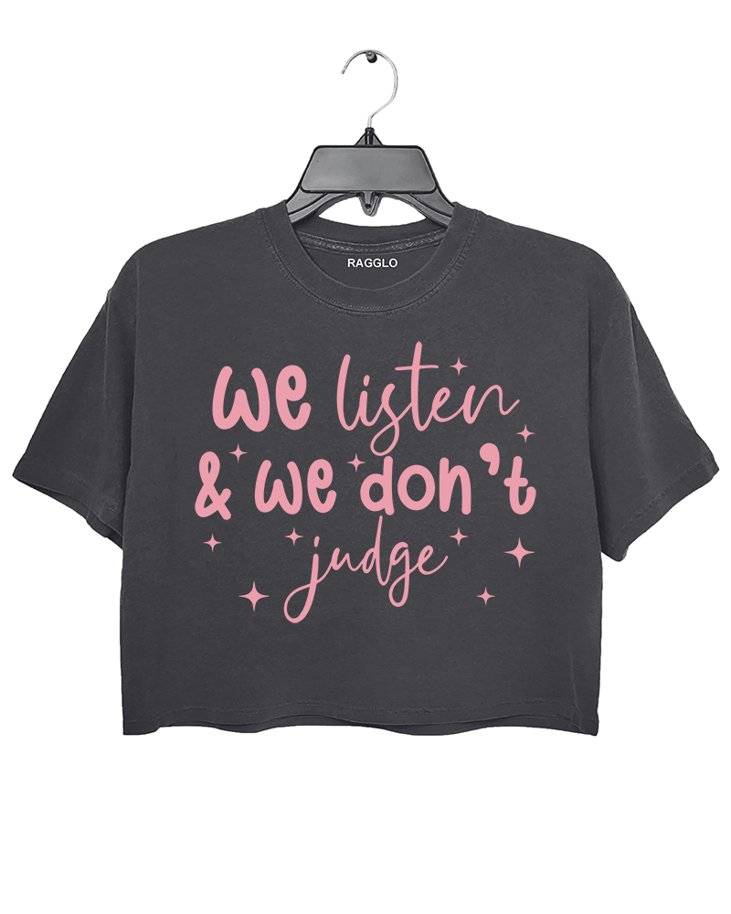 A dark gray cropped t-shirt from Ragglo with the text "We listen & we don't judge" in pink, decorated with star accents.

