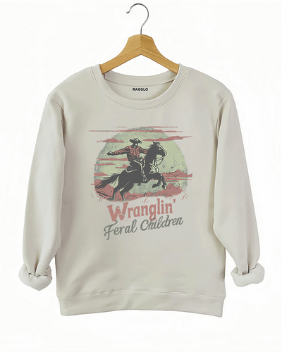 Ragglo beige sweatshirt featuring a western-themed cowboy on horseback with the text 'Wranglin' Feral Children,' in a vintage design style with dusty desert tones.