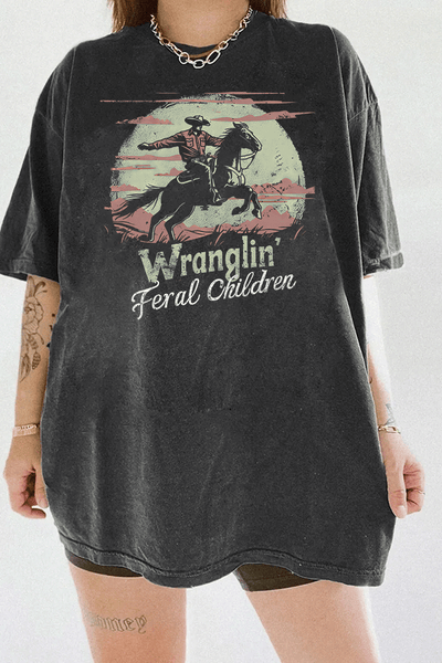 Ragglo dark gray T-shirt with a vintage cowboy design, highlighting a cowboy on horseback with the text 'Wranglin' Feral Children' set against a desert backdrop.